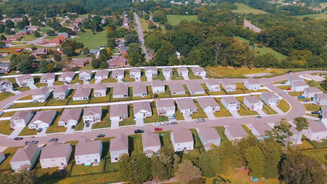 Aerial drone view of Mockingbird Meadows, a new-construction neighborhood of single-family homes on curved streets surrounded by trees in Halls, North Knoxville, Tennessee