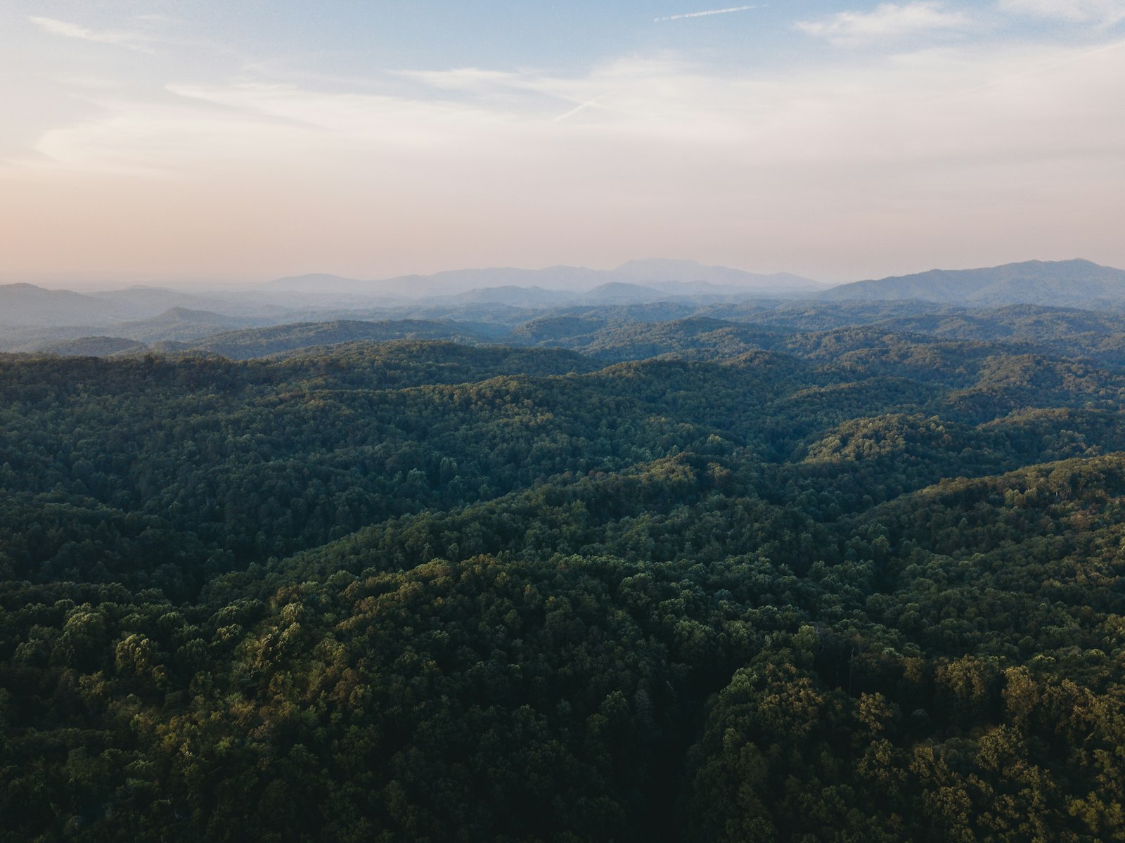 Aerial view of forested Appalachian foothills rolling toward the hazy Great Smoky Mountains at sunset, about 45 minutes from Knoxville, Tennessee